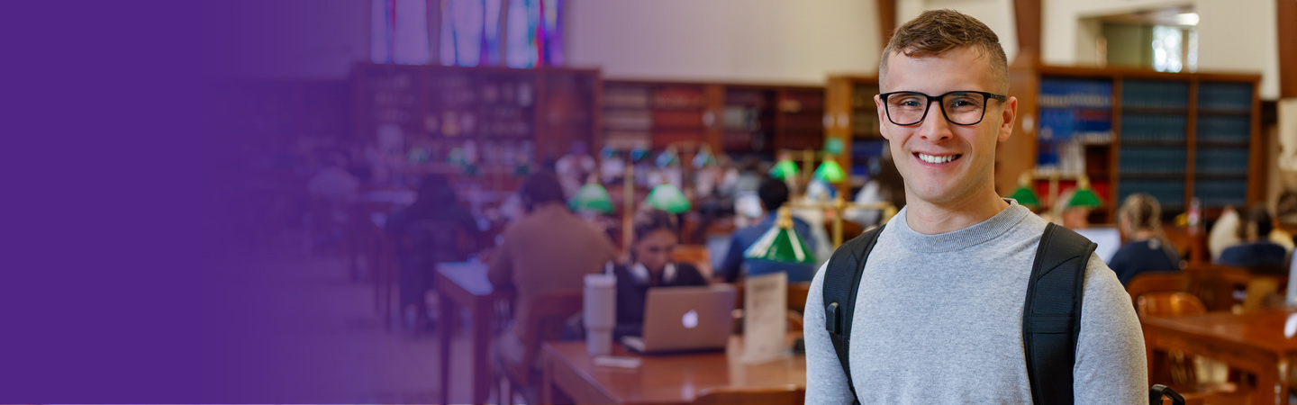 Law student Mason Bruner-Moore smiles in front of tables in the law library.
