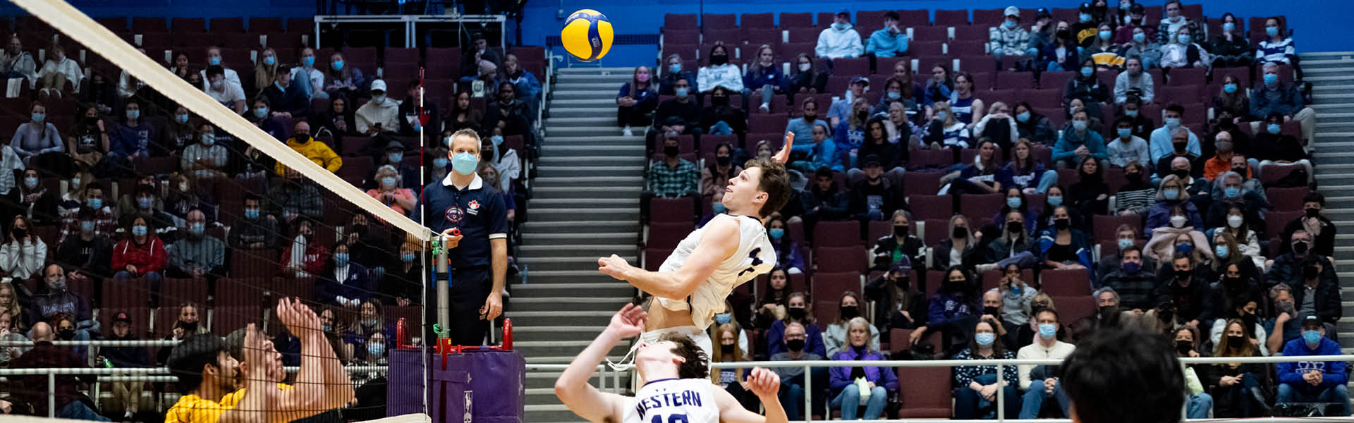 Western Mustangs men’s volleyball player jumping to spike the ball