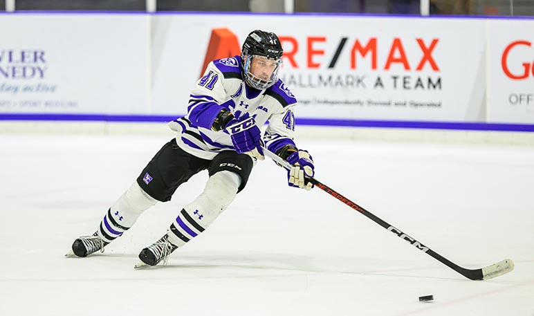 Western Mustangs men’s hockey player skating with the puck