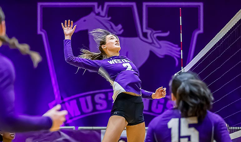 Western Mustangs women’s volleyball player jumping to serve the ball