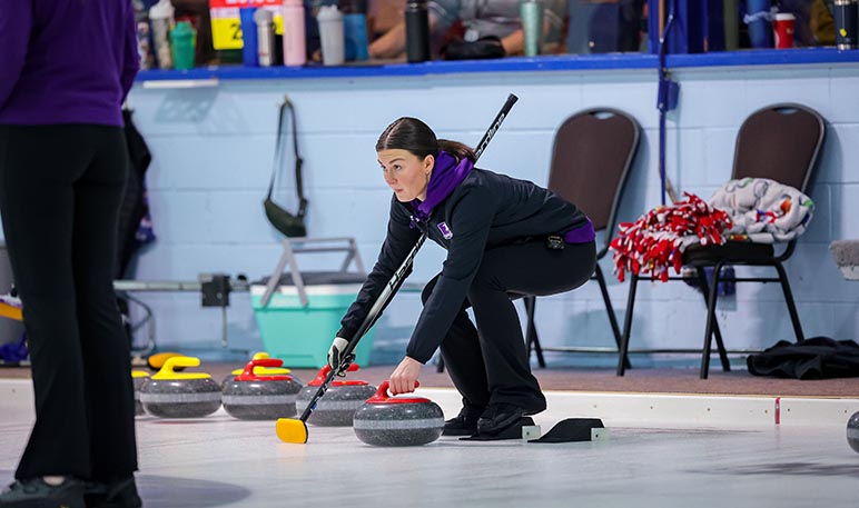 Western Mustangs men’s curler delivers a stone while his teammates sweep