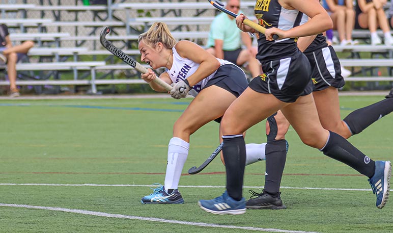Western Mustangs field hockey player lunging and swinging her stick