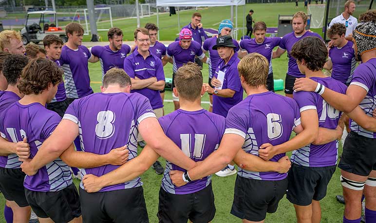 Western Mustangs men’s rugby team huddled in a circle with their arms up