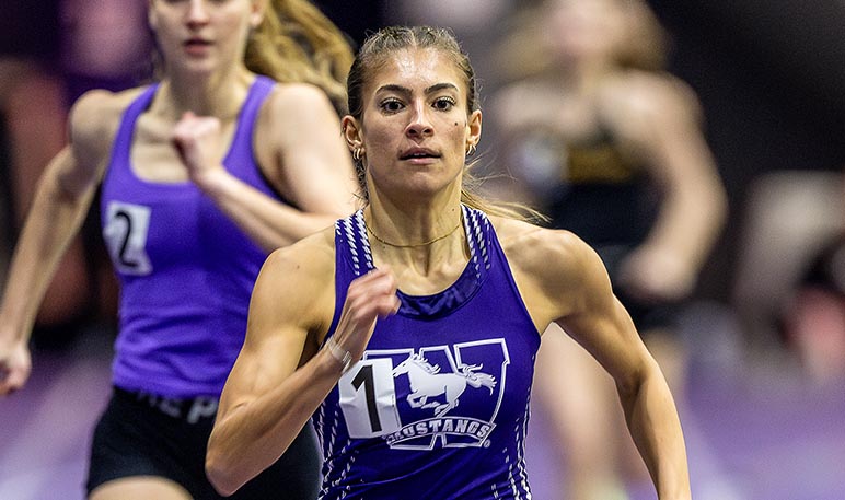Western Mustangs female relay runner reaching back to receive the baton from her teammate