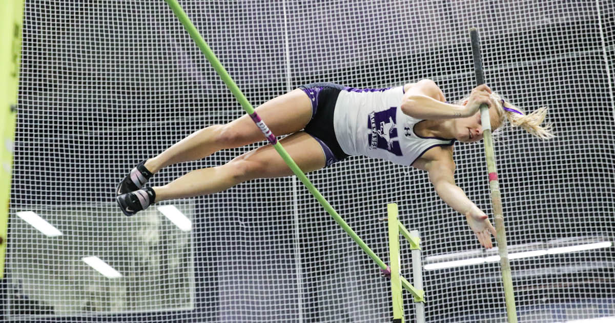 Western Mustangs female pole vaulter mid-jump