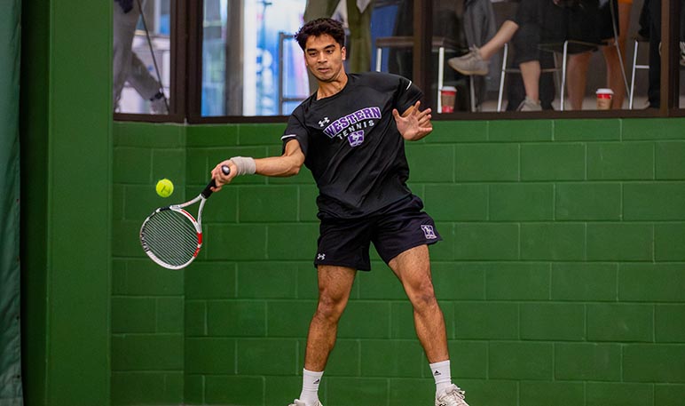 Western Mustangs men’s tennis player preparing to serve the ball