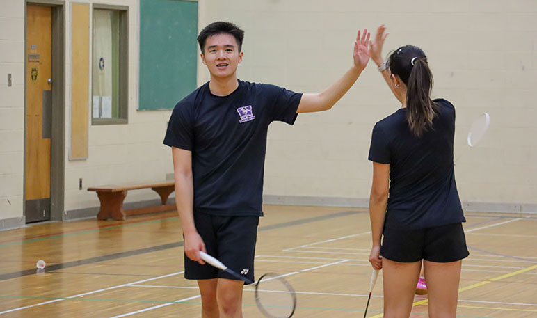Western Mustangs women's doubles badminton players mid-game